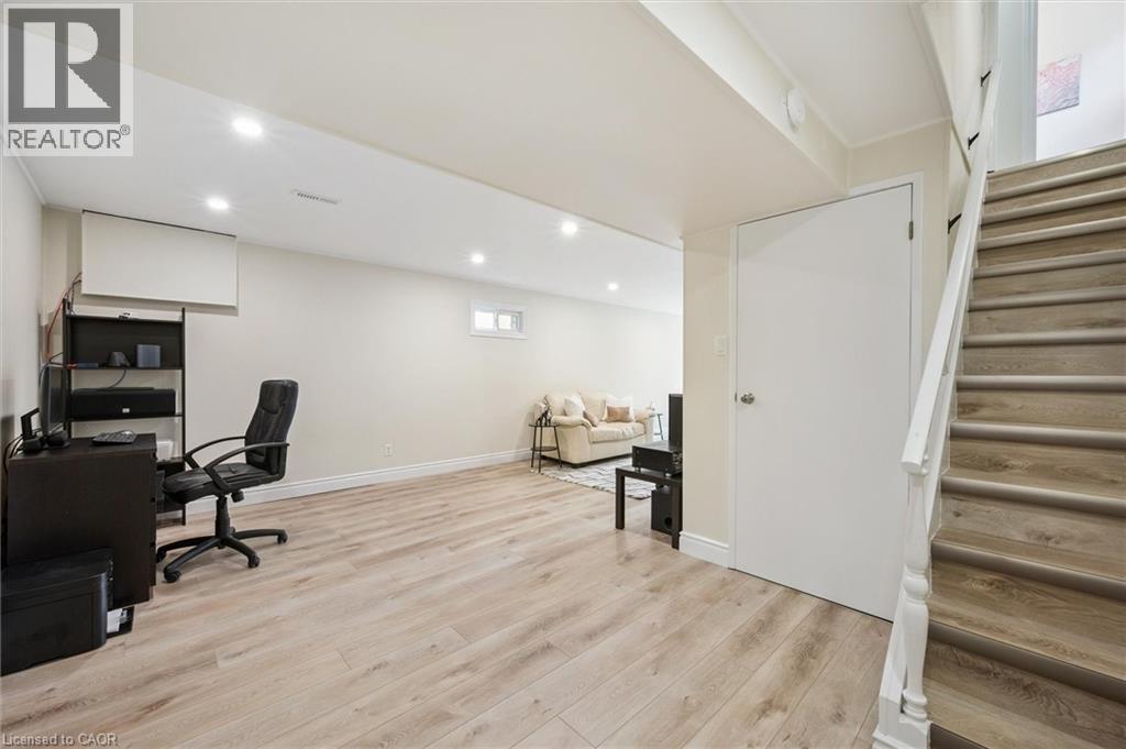Spacious lower level featuring light wood-finish flooring, recessed lighting, a neutral color palette, a visible window, and a finished staircase with white risers and handrail