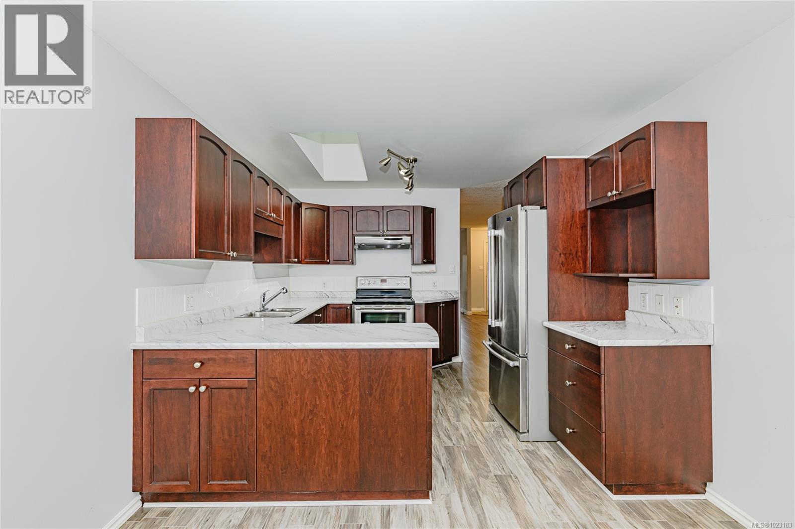Kitchen is functionally laid out, sky light for extra lighting and tiled back splashes.