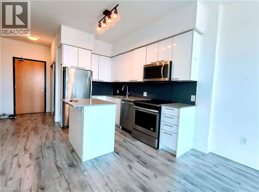 The kitchen features white cabinetry, stainless steel appliances, and a dark tile backsplash