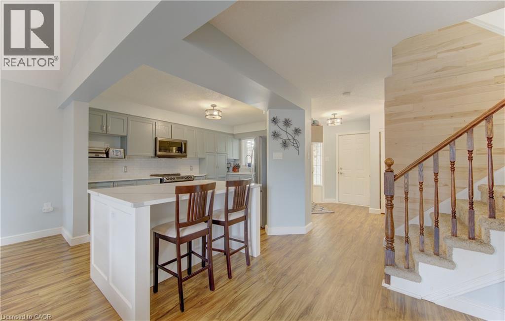 Open-concept kitchen featuring an island with white paneling and a light-toned countertop