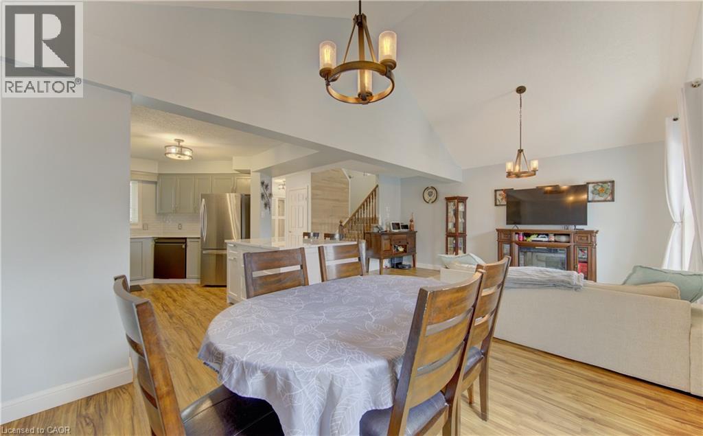 Open-concept living area featuring wood-finish flooring, vaulted ceilings, and a kitchen with stainless steel appliances