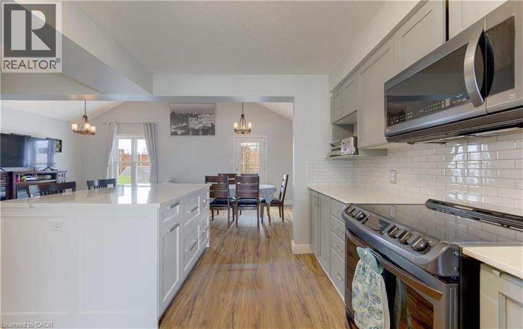 Open-concept kitchen with a white center island featuring integrated storage, light wood-finish flooring, and white subway tile backsplash