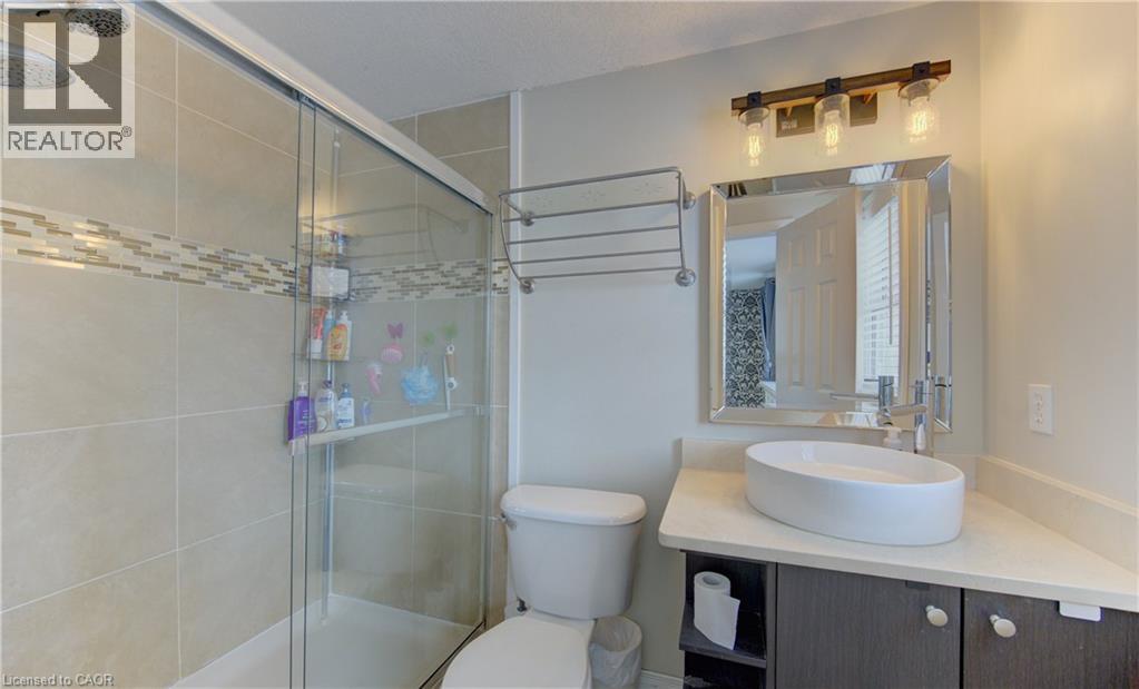 Bathroom featuring a glass-enclosed shower with tile surround and decorative mosaic accent band