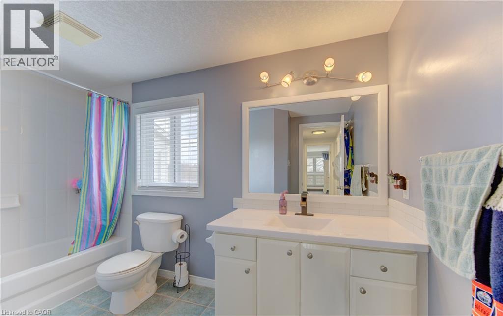 Bathroom featuring a white vanity with integrated sink, a large wall-mounted mirror, a modern vanity light fixture, and a window with blinds