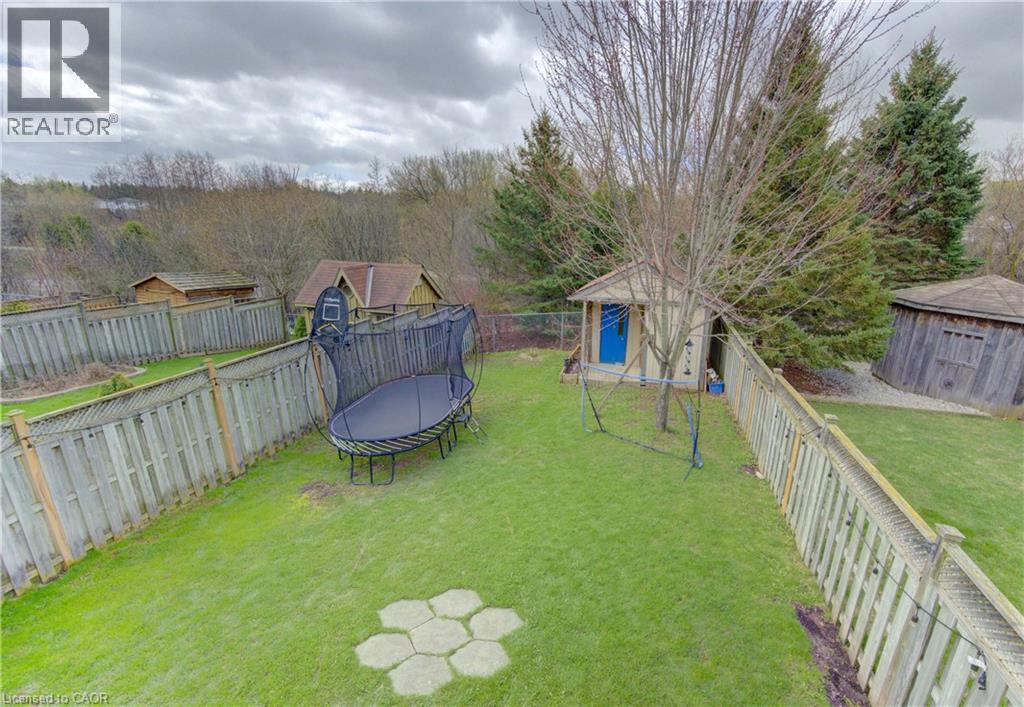 Expansive backyard featuring a manicured lawn, established privacy fencing, a separate storage shed with a blue door, and a circular gazebo structure