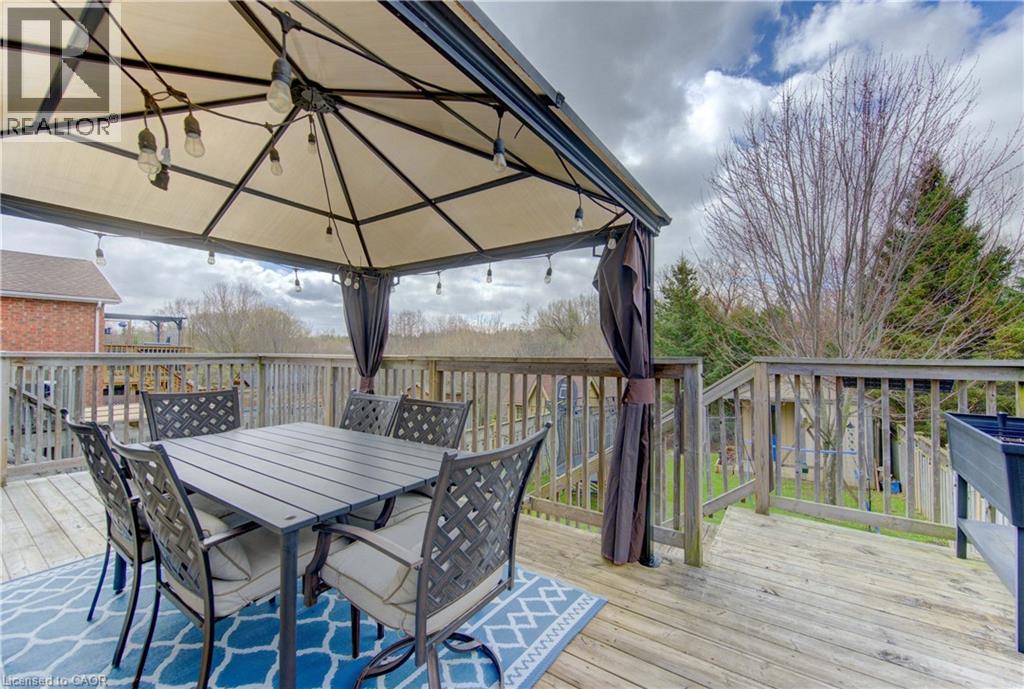 Expansive wooden deck featuring a built-in gazebo with string lighting, wooden railing, and an outdoor planter box