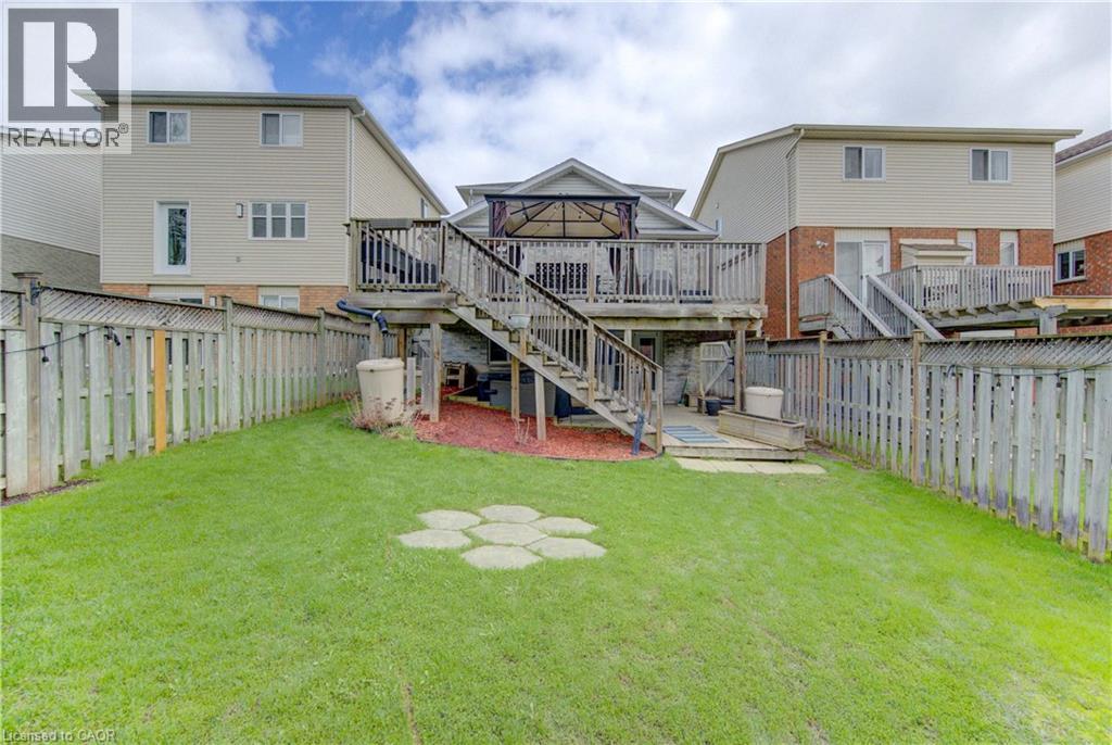 Expansive backyard featuring a manicured lawn, full privacy fencing, and a multi-level wood deck