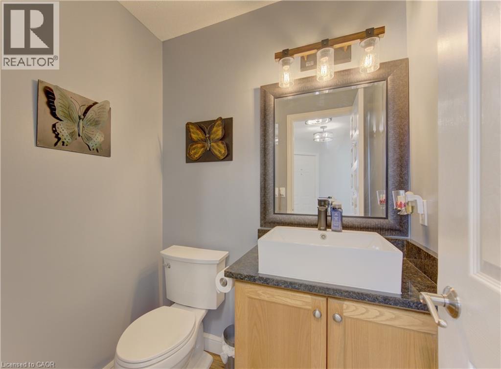 Powder room featuring a vessel sink, dark countertop, and wood-finish cabinetry