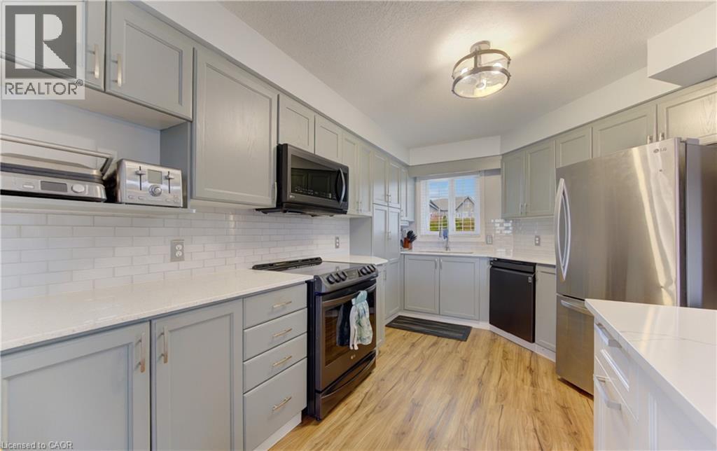 Kitchen featuring light gray cabinetry with brushed nickel hardware, white subway tile backsplash, white countertops, and wood-finish flooring