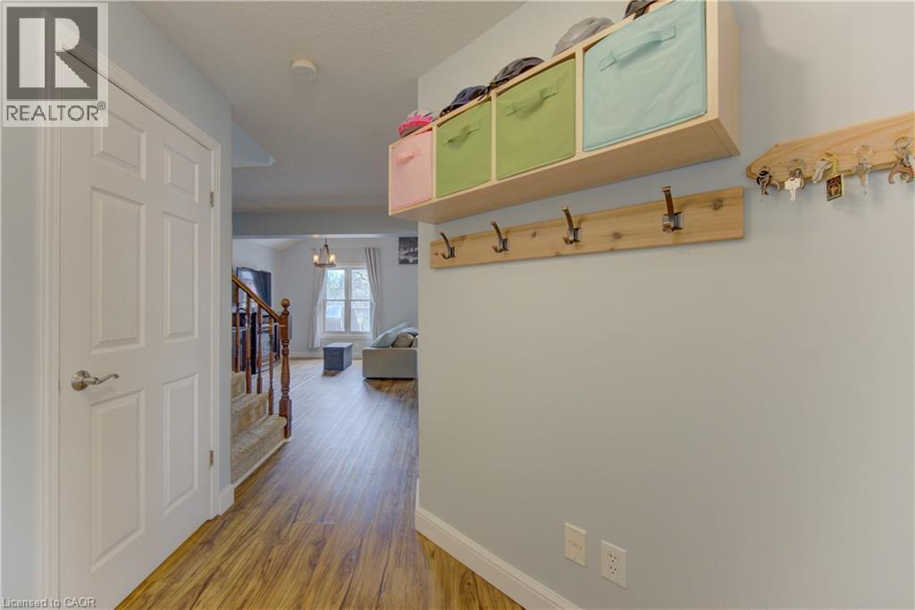 Entryway featuring wood-finish flooring, a six-panel interior door, and a staircase with a wooden handrail and carpeted treads