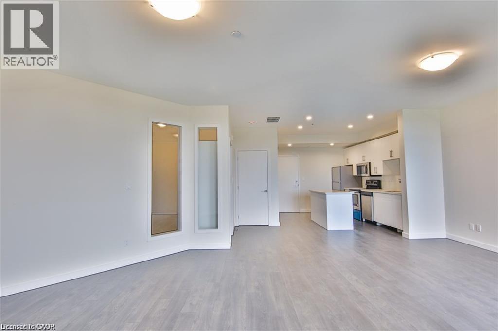 Unfurnished living room featuring light wood finished floors and baseboards
