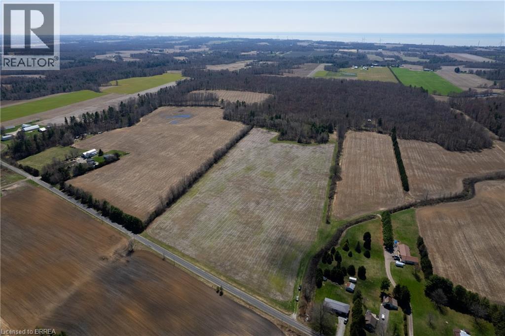 Expansive agricultural land featuring multiple fields, wooded areas, and a visible roadway