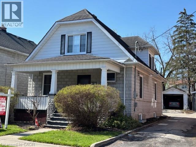 Traditional home featuring a covered front porch with classic columns, a stone façade, and dormer window with contrasting shutters