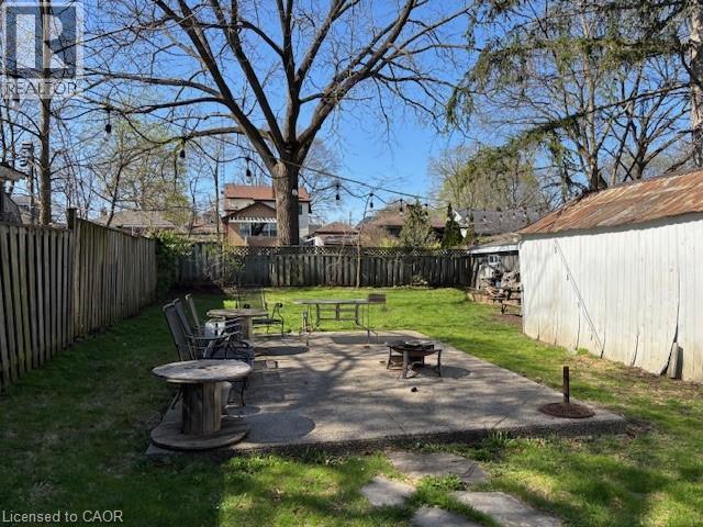 Expansive backyard featuring a concrete patio, a privacy fence, and a storage shed