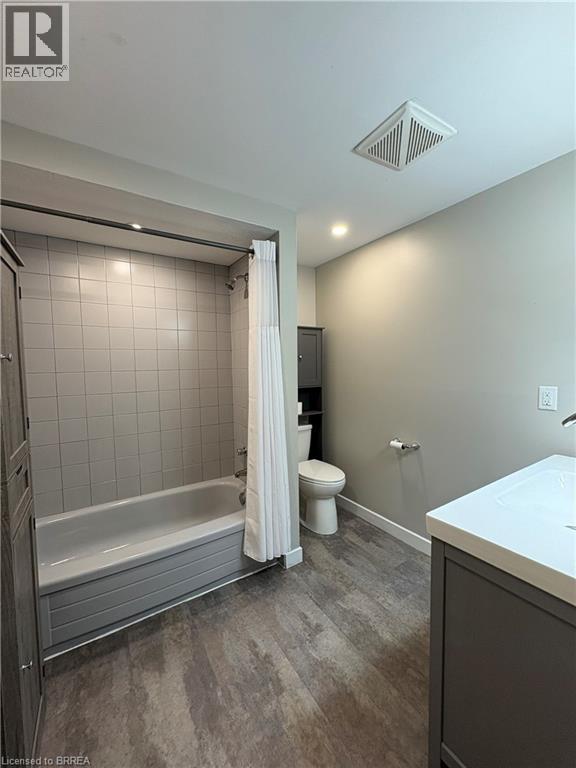 Bathroom featuring vanity, dark wood finished floors, shower / tub combo with curtain, and recessed lighting