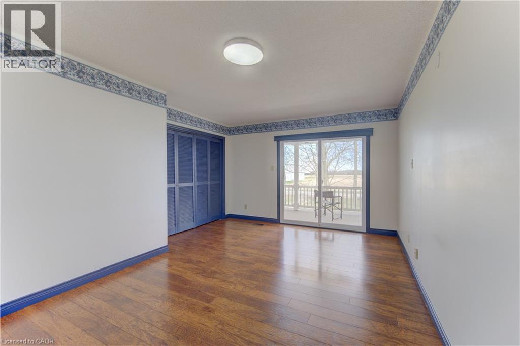 Bedroom with wood-finish flooring, sliding glass door to exterior balcony, and bi-fold louvered closet doors