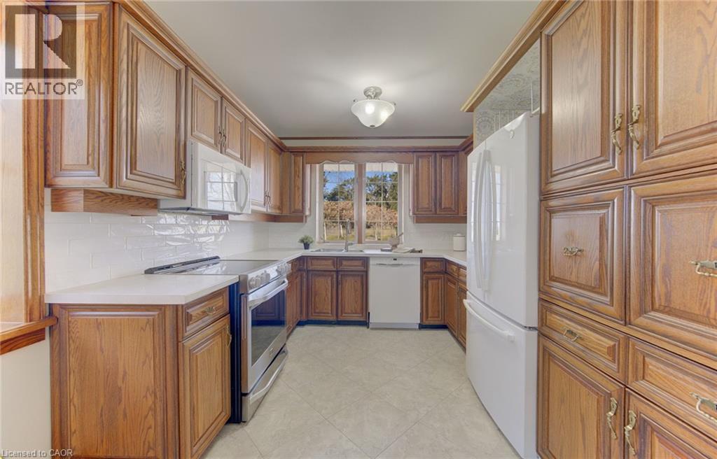 U-shaped kitchen featuring wood cabinetry, white solid-surface countertops, and a white subway tile backsplash
