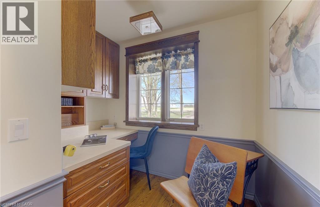 Dedicated workspace featuring a built-in wood-finish desk, ample cabinetry with gold-tone hardware, and a window with wood trim