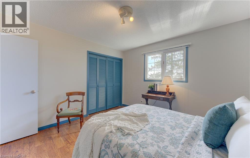 Bedroom featuring wood-finish flooring, a double window with blue trim, and louvered bi-fold closet doors