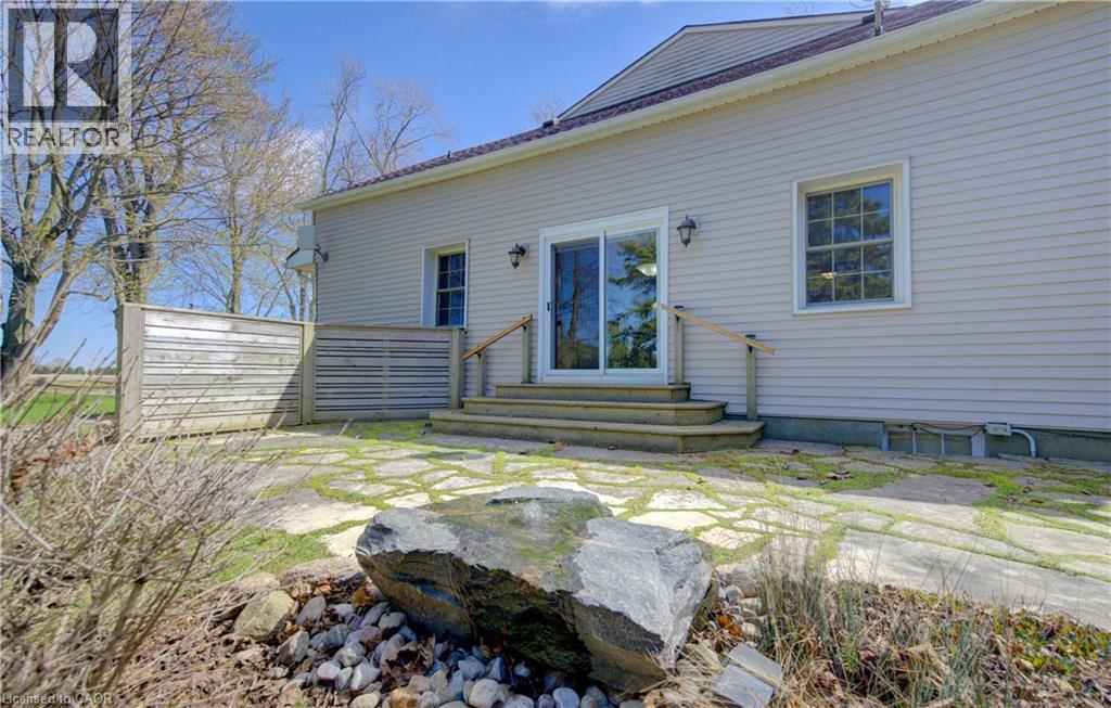 Rear exterior featuring light-colored siding, a stone patio, and a privacy fence