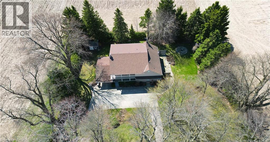 Property featuring a multi-level structure with a brown shingle roof, surrounded by mature trees