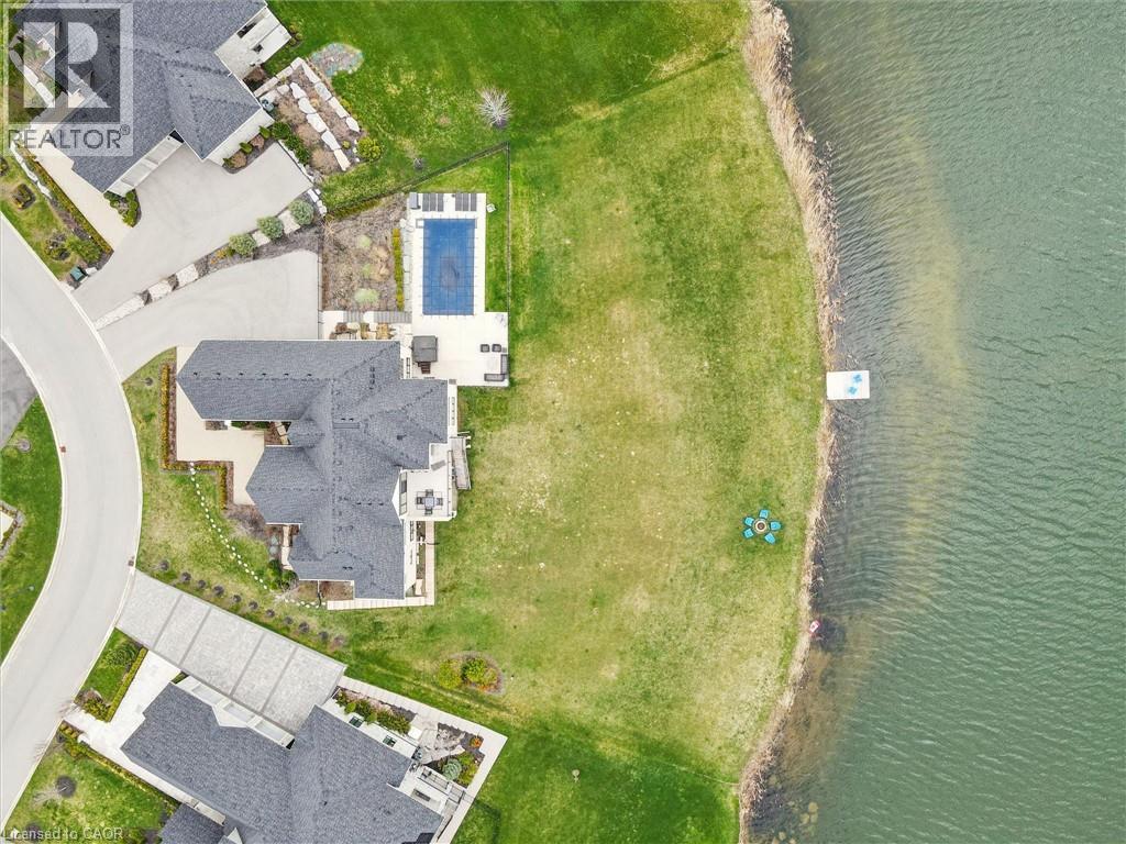 Waterfront property featuring a private dock, expansive green lawn, and a large private pool with an adjacent patio