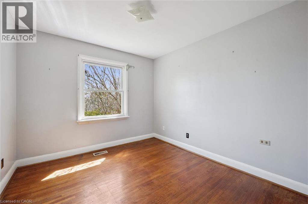 Room featuring wood-finish flooring, light gray walls, white trim, and a white framed window