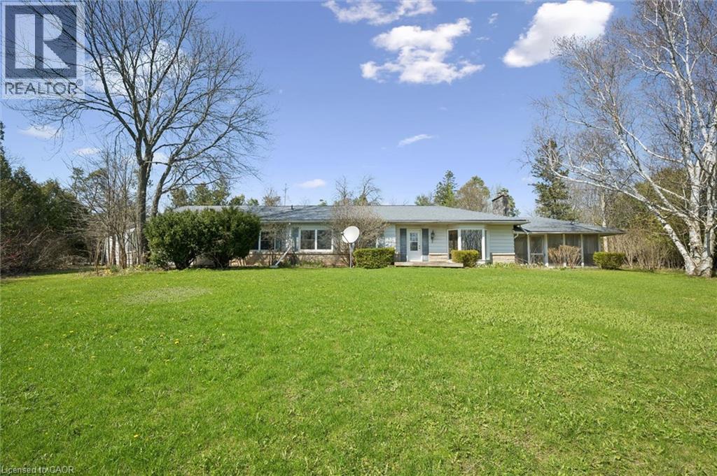 Ranch-style residence featuring a light-colored exterior, green metal roof, and a screened porch