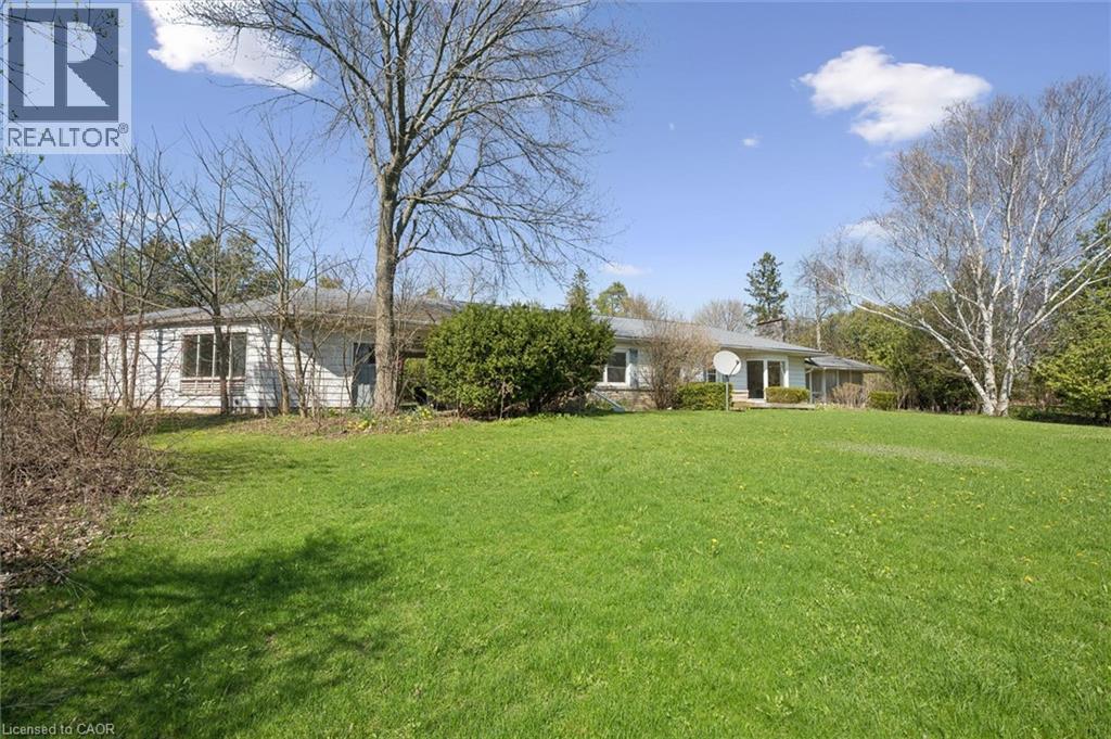 Expansive grassy lawn bordering a single-story residence with white siding and multiple windows