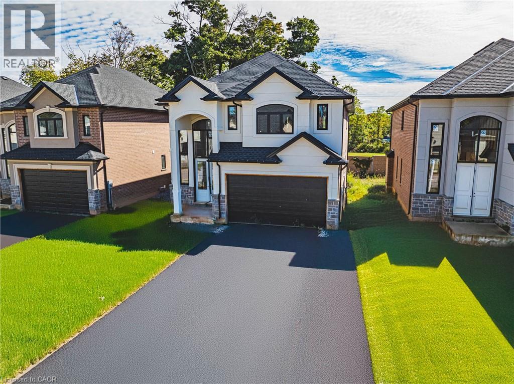French country inspired facade with a front lawn, a garage, stone siding, and asphalt driveway