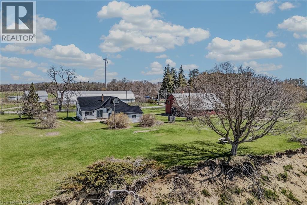 Expansive green grounds featuring a white residential structure with a dark roof, a red barn, and a wind turbine