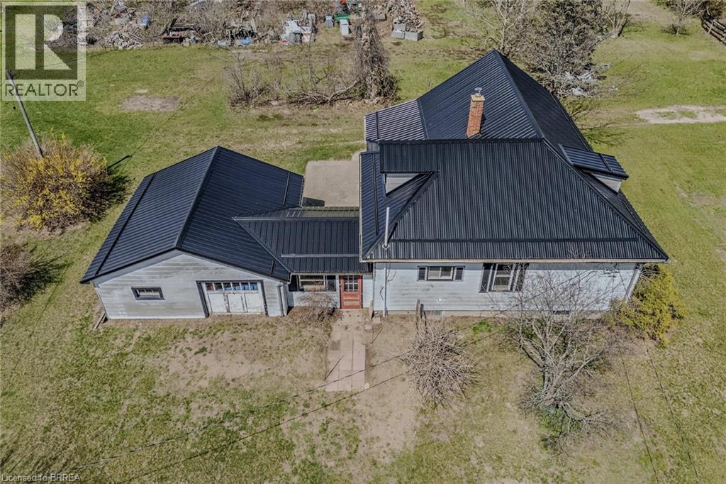 Property featuring a dark metal roof, light-colored siding, and a prominent chimney