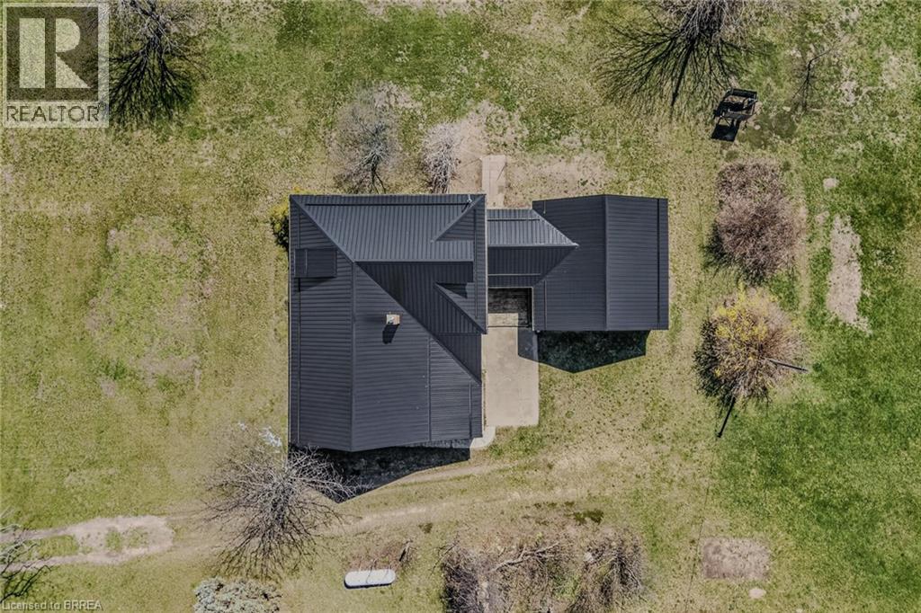 Modern dwelling featuring a dark metal roof, dark siding, and a concrete pathway