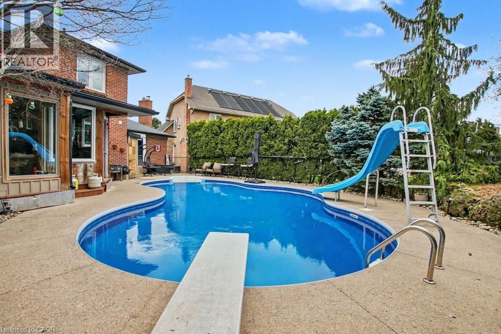 Freeform inground pool with concrete surround, diving board, and integrated slide