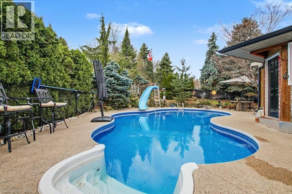 Rear yard featuring a freeform swimming pool with integrated spa and surrounding concrete patio