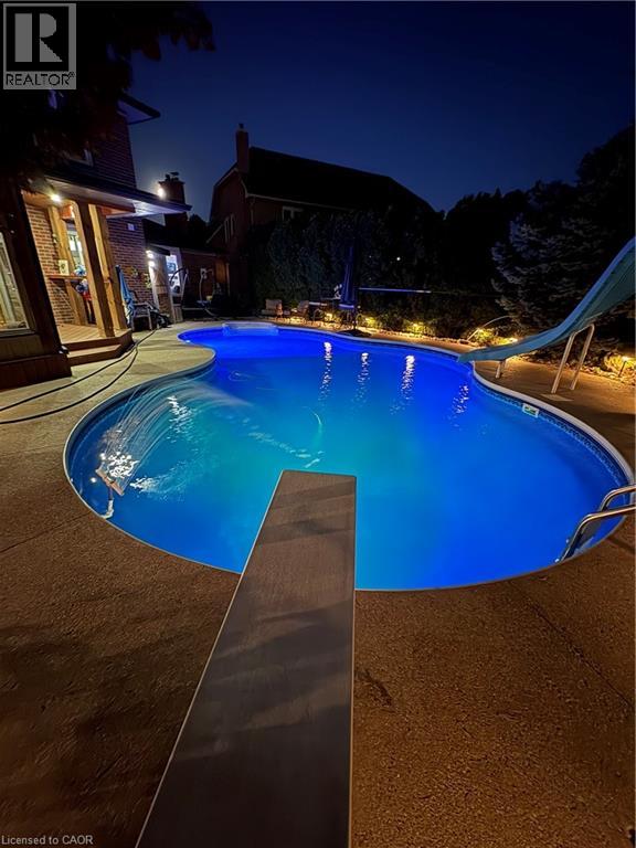 Freeform swimming pool with integrated diving board, waterslide, and surrounding textured concrete decking