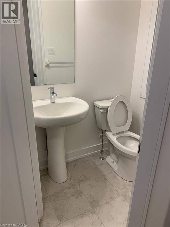 Powder room featuring a pedestal sink with a chrome faucet, a standard toilet, and neutral-toned wall paint