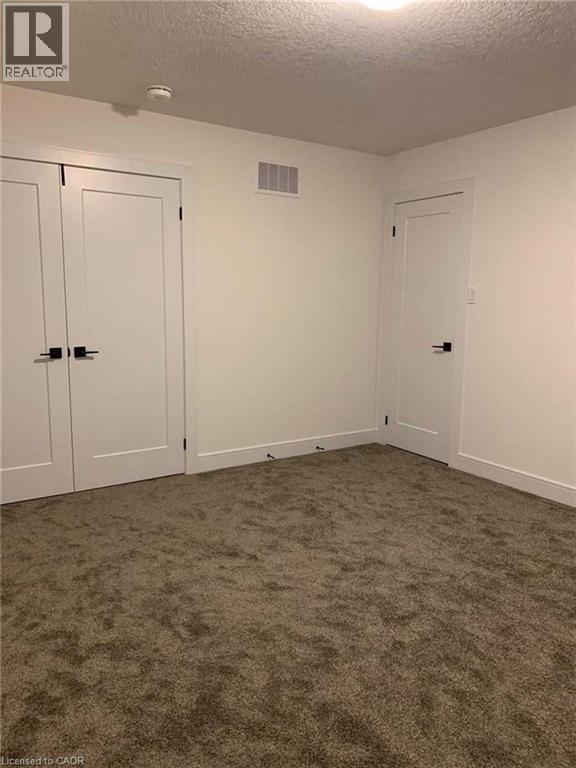 Carpeted room featuring white walls, white trim, and two white doors with black hardware