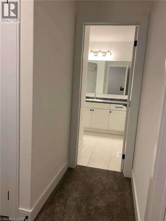 Contemporary bathroom featuring a white vanity with dark countertop, large mirror, and three-bulb light fixture