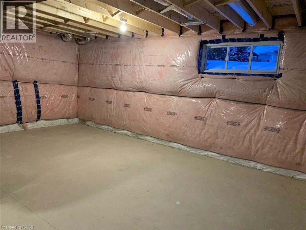 Unfinished basement featuring exposed wood joists, insulated walls, concrete flooring, and a single window