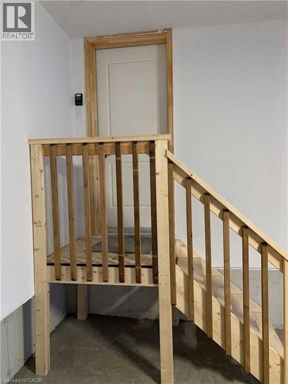 Unfinished wooden staircase with balustrade, leading to a white paneled door with unfinished wood trim