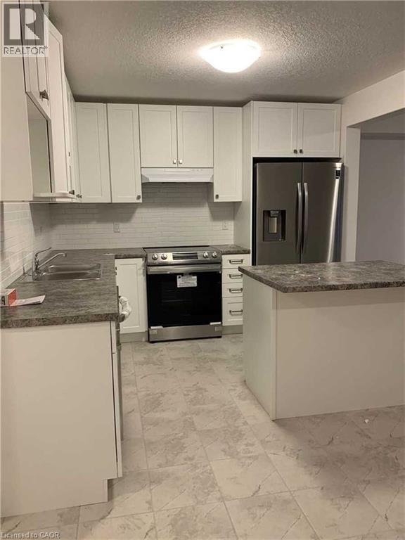 Modern kitchen featuring white cabinetry, stone-finish countertops, stainless steel appliances, and a subway tile backsplash