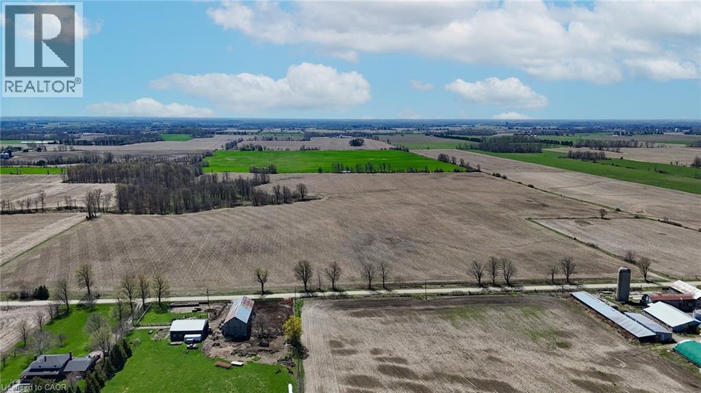Expansive agricultural landscape featuring open fields, scattered mature trees, and multiple farm buildings