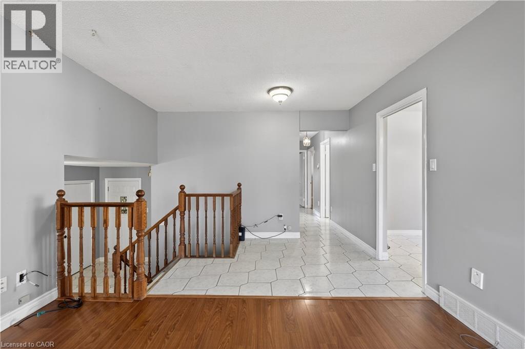 Hallway featuring an upstairs landing, light wood-style floors, and a textured ceiling