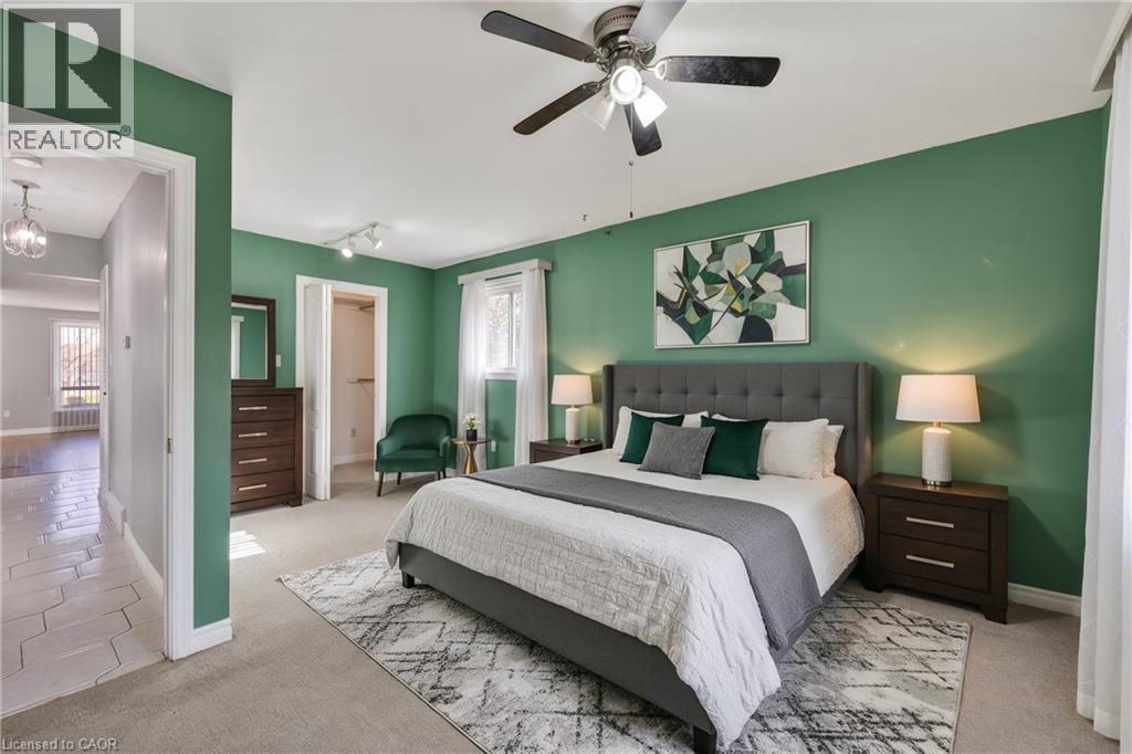 Bedroom featuring light colored carpet, multiple windows, and ceiling fan