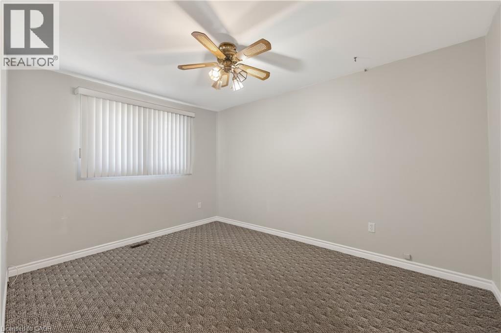 Empty room with dark colored carpet and a ceiling fan