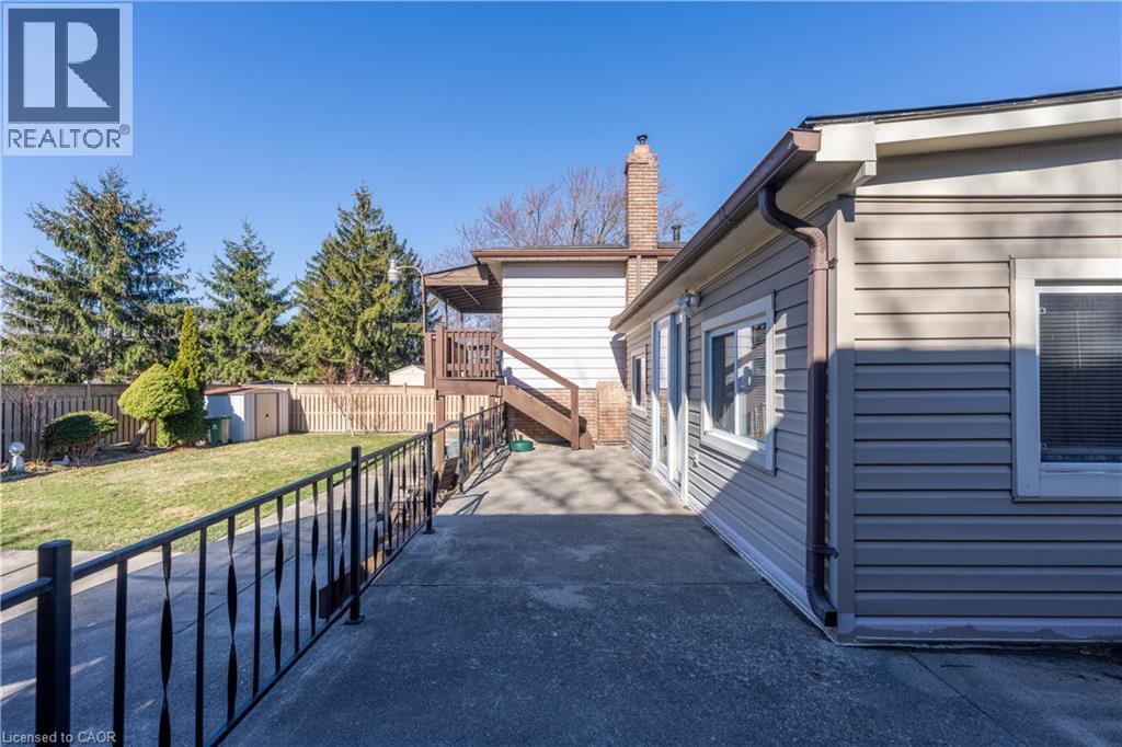 View of property exterior featuring a patio area, a storage shed, a fenced backyard, and a chimney