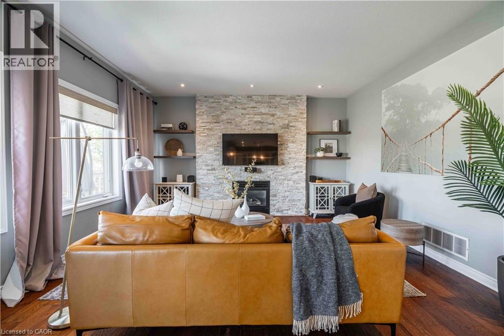 Family Room with a stone fireplace and huge window overlooking deck and greenspace beyond