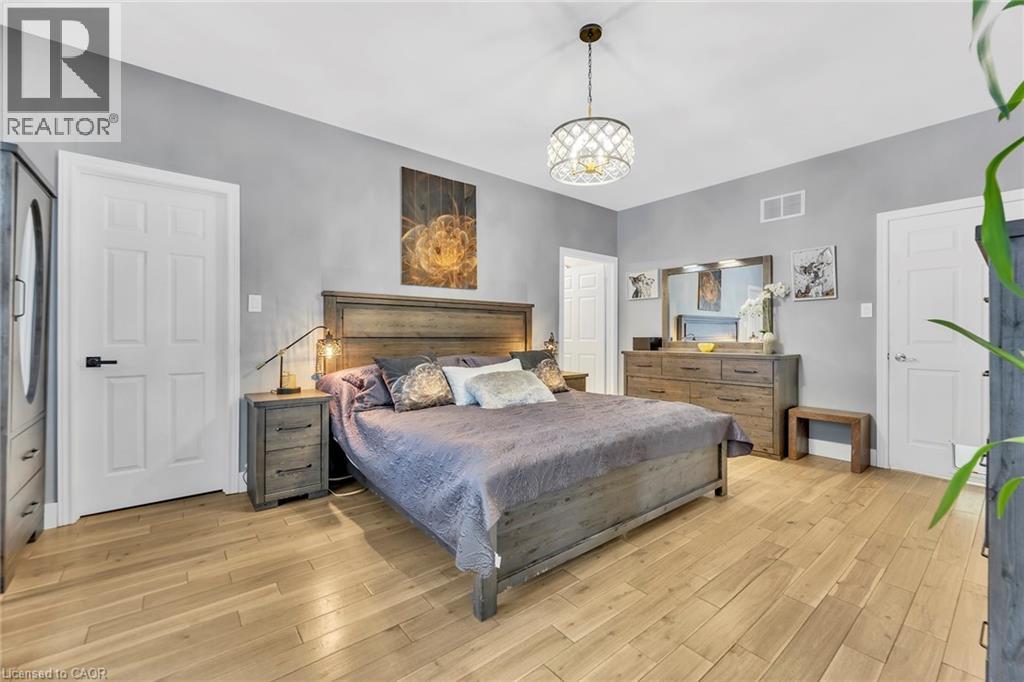 Spacious room featuring light wood-finish flooring, a contemporary ceiling light fixture, and multiple white panel doors
