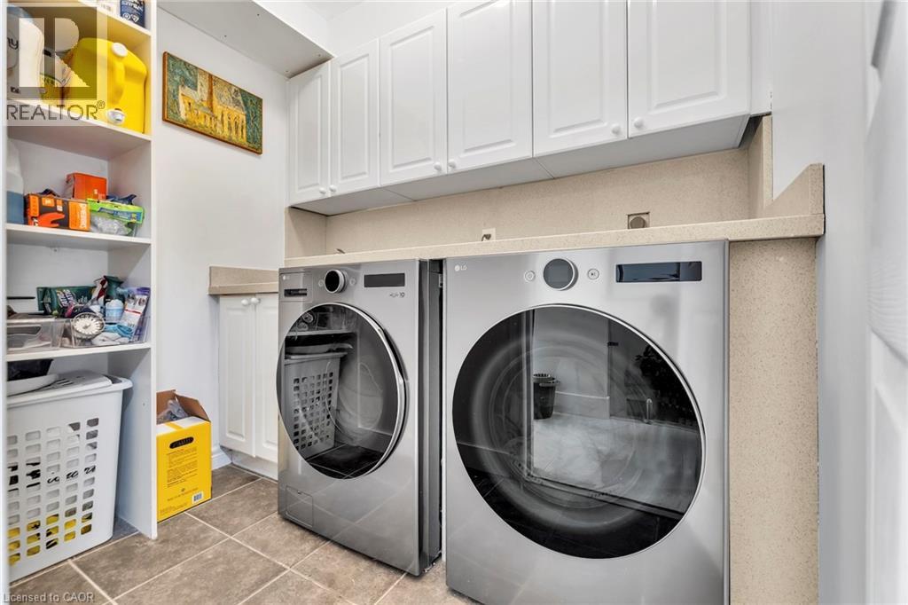 Laundry area featuring a side-by-side washer and dryer, white shaker-style cabinetry, a light-toned countertop, and tiled flooring
